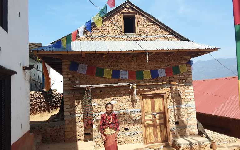 an elderly in front of her newly built house.